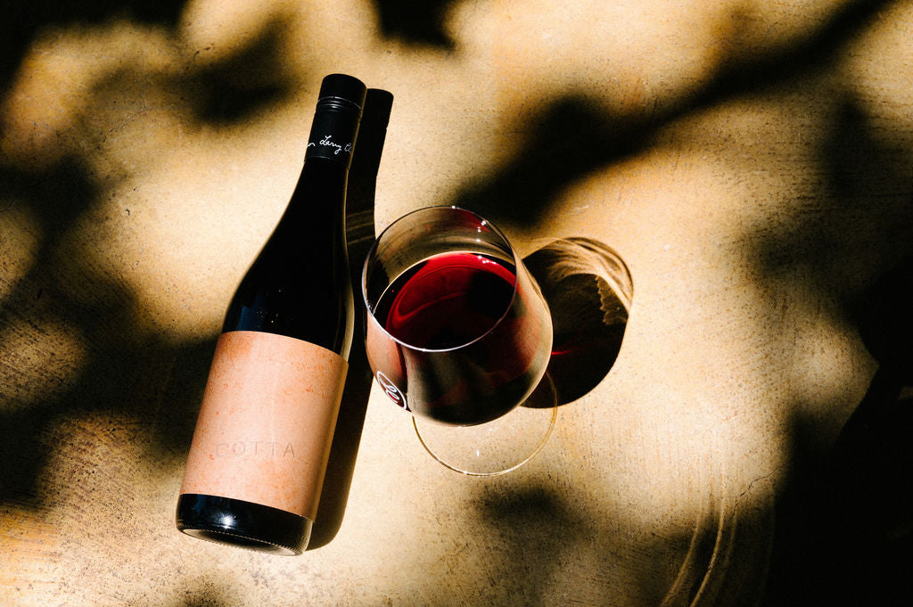 Wine bottle and two glasses with red wine on a textured surface