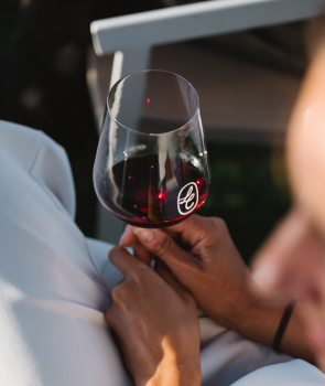 Person holding a glass of red wine with a blurred background